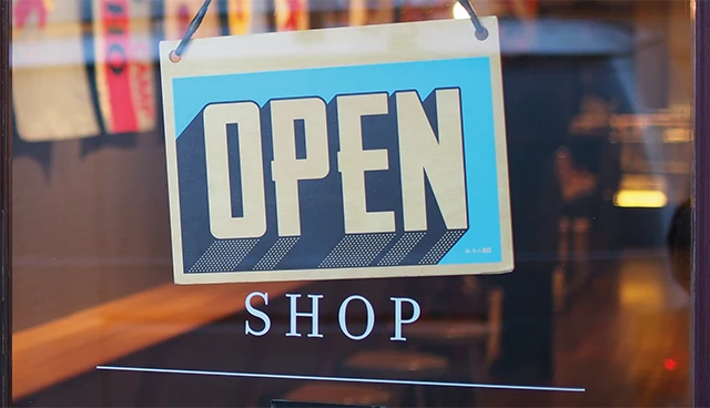 Schild mit der Aufschrift OPEN SHOP an einer Ladentür, repräsentiert das SyShop-System von SyLinx, das eine direkte Anbindung an die SelectLine Warenwirtschaft bietet.